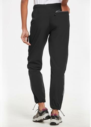 Back view of person wearing black joggers and sneakers.