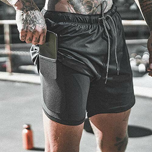 Man wearing gym shorts with phone in pocket.