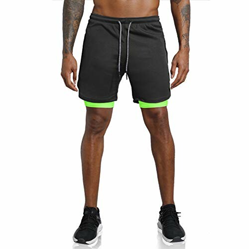Man wearing black sports shorts with green trim and black sneakers.