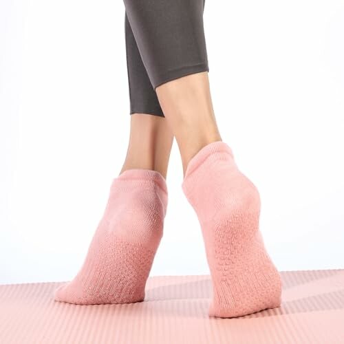 Person wearing pink grip socks on yoga mat