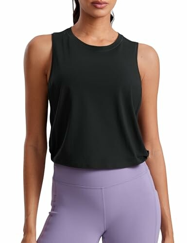 Woman wearing a sleeveless black top and purple leggings