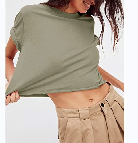 Woman wearing a green shirt and beige pants, lifting shirt slightly.