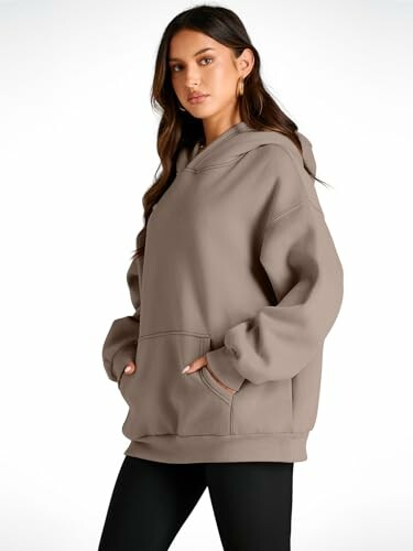 Woman in oversized taupe hoodie and black leggings