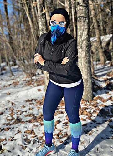 Woman in winter running gear standing in a snowy forest