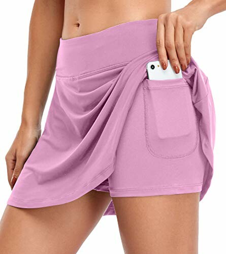 Woman wearing a pink tennis skirt with a side pocket holding a smartphone.